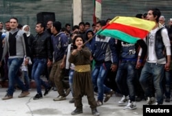 FILE - A Kurdish boy waves a Kurdish flag during celebrations after it was reported that Kurdish forces took control of the Syrian town of Kobani, in Sheikh Maksoud neighborhood of Aleppo, Jan. 27, 2015.