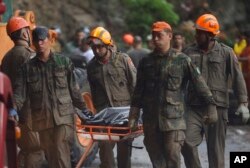 Firefighters and soldiers remove a body recovered from an area where heavy rains caused a mudslide half-burying several vehicles and uprooting trees, in Rio de Janeiro, Brazil, April 9, 2019.