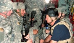 FILE - U.S. Senator and Democratic presidential candidate Joe Biden, right, talks with soldiers as he travels in a military vehicle to Iraq from Kuwait in this Sept. 6, 2007, handout photo.