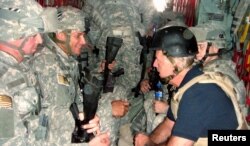 FILE - U.S. Senator and Democratic presidential candidate Joe Biden, right, talks with soldiers as he travels in a military vehicle to Iraq from Kuwait in this Sept. 6, 2007, handout photo.