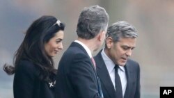 Aktor Amerika George Clooney (kanan) dan istrinya Amal, bersama penasihat kebijakan kanselir Angela Merkel, Christoph Heusgen, di Berlin (12/2). (AP/Markus Schreiber)