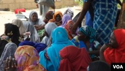 Quelques femmes assises attendent la distribution de nourriture dans un camp, Maiduguri, Nigeria, septembre 2016. (Photo: C. Oduah)