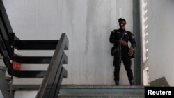 FILE - A police officer stands guard before the bail hearing of 21 people who were detained by police and accused of unlawful assembly and promoting an LGBTQ agenda, in Ho, Volta region, Ghana, June 4, 2021. 