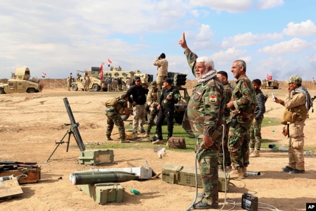 Iraqi army soldiers and volunteers, such as Iranian-backed Shiite militias and Sunni tribes, prepare to launch mortar shells and rockets against Islamic State militant positions outside Tikrit, March 4, 2015.