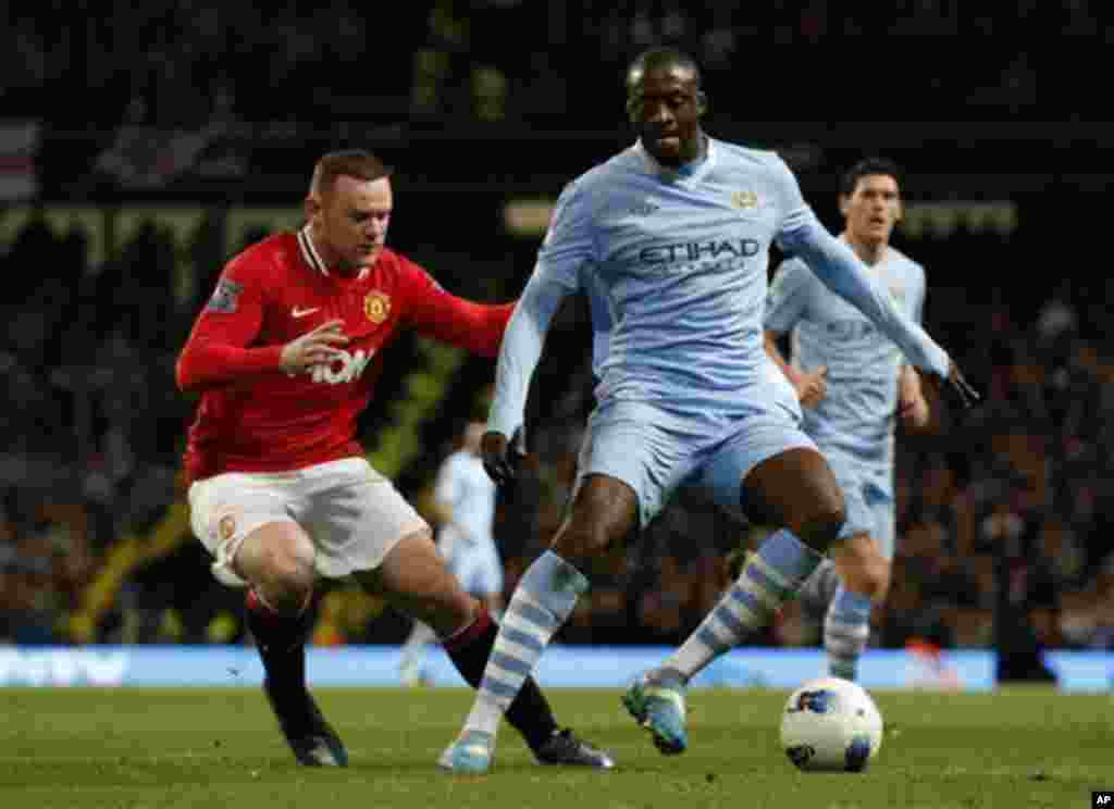 Manchester City's Yaya Toure, right, competes for the ball with Manchester United's Wayne Rooney during the English Premier League soccer match between Manchester City and Manchester United at the Etihad Stadium in Manchester, Monday, April 30, 2012. (AP