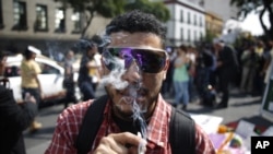 FILE - A supporter of the legalization of marijuana smokes outside the Supreme Court in Mexico City, Nov. 4, 2015.