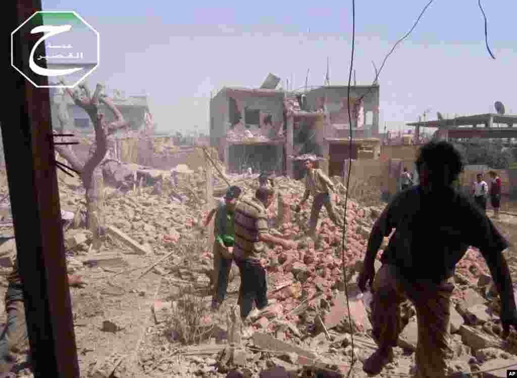 Gambar yang diambil oleh jurnalisme warga Qusair Lens, dan telah diverifikasi oleh kantor berita AP, memperlihatkan warga Suriah yang memeriksa puing-puing bangunan yang hancur karena serangan udara pemerintah di Qusair (18/5).