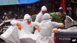 Health workers load the body of an amputee suspected of dying from the Ebola virus during the rain on the back of a truck, in a busy street in Monrovia, Liberia, Sept. 2, 2014.