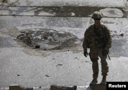 A NATO soldier stands at the site of a suicide car bomb blast in Kabul, Afghanistan, Oct. 11, 2015.