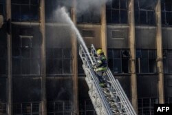 FILE - A firefighter extinguishes the fire at a building in Johannesburg on August 31, 2023.