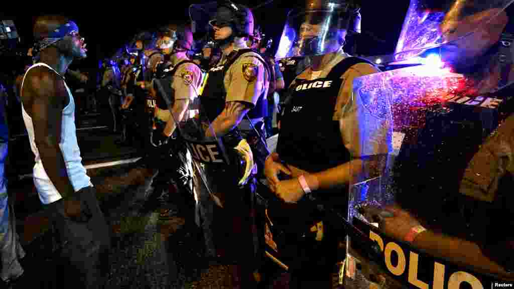Des policiers montent la garde alors que les manifestants marchent sur West Florissant à Ferguson, 9 août 2015.