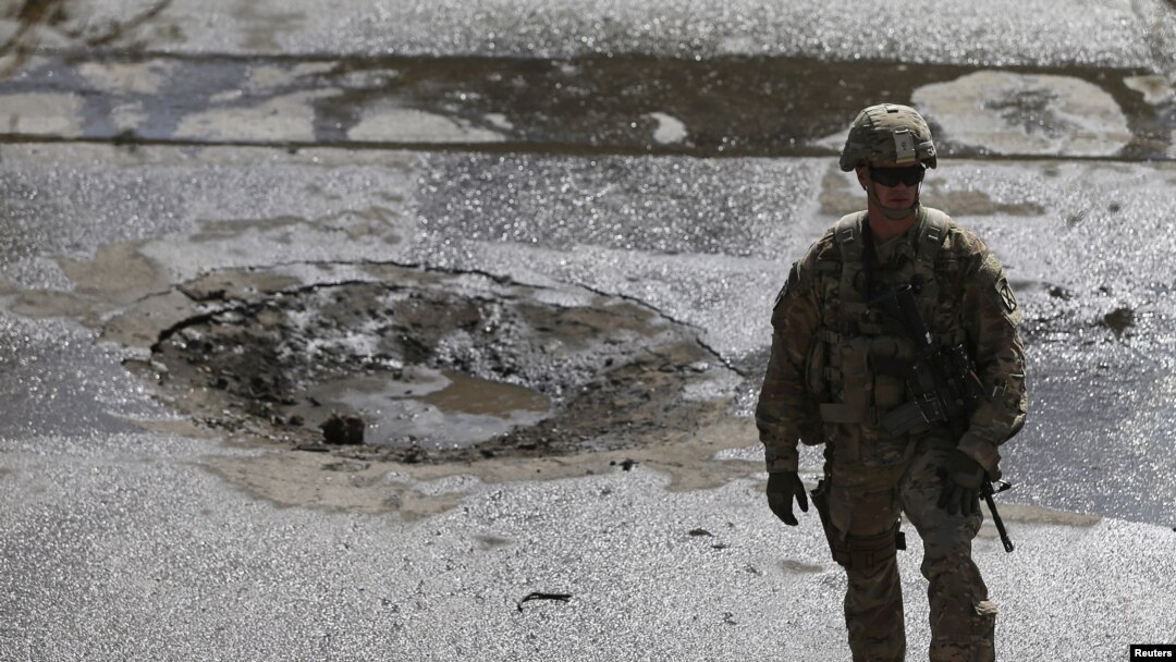 Seorang tentara NATO berdiri di lokasi bom bunuh dire di Kabul, Afghanistan, 11 Oktober 2015. (REUTERS/Mohammad Ismail)