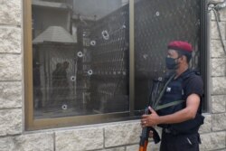 A police officer stands guard next to a bullet riddled window at the Pakistan Stock Exchange building after an attack in Karachi, June 29, 2020.