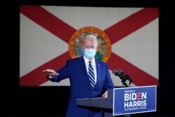 FILE - The Florida state flag hangs behind Democratic presidential candidate former Vice President Joe Biden as he speaks at Southwest Focal Point Community Center in Pembroke Pines, Fla., Oct. 13, 2020.