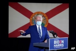 FILE - The Florida state flag hangs behind Democratic presidential candidate former Vice President Joe Biden as he speaks at Southwest Focal Point Community Center in Pembroke Pines, Fla., Oct. 13, 2020.