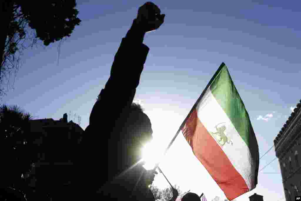 A demonstrator shouts slogans near the flag of the former Imperial State of Iran as he gathers with supporters of Maryam Rajavi, head of the Iranian opposition group National Council of Resistance, outside the Iran Embassy, in Rome, Jan. 2, 2017. 
