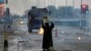 FILE - A female protester holds a photo of Shi'ite scholar Isa Qassim as she confronts riot police armoured personnel carrier during a demonstration to mark the 6th anniversary of the February 14 uprising, in the village of Sitra, south of Manama.