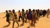 FILE - Migrants from Ethiopia, Sudan and Chad, who were abandoned by traffickers in a remote desert area near the Libyan border, walk after being arrested by Sudan's paramilitary Rapid Support Forces on the Khartoum State border, Sudan, Sept. 25, 2019.