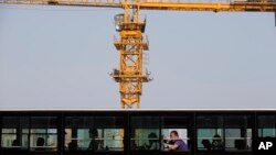 A man yawns in a bus which drives past a construction site in Beijing, China, April 29, 2014.