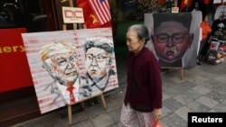 Seorang perempuan berjalan melintas di depan lukisan gambar Pemimpin Korea Utara Kim Jong Un dan Presiden AS Donald Trump menjelang KTT AS-Korut kedua di Hanoi, Vietnam, 27 Februari 2019.