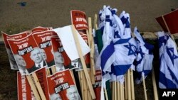 Israeli flags lie on the ground with signs showing the faces of Israeli Prime Minister Benjamin Netanyahu (R) and ex-rival Benny Gantz (L) with a caption in Hebrew reading 'Israeli ashamed' during a May 14, 2020, demonstration against the new government.