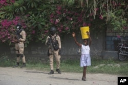 A street vendor walks past police officers ahead of the arrival of U.S. Secretary of State Antony Blinken in Port-au-Prince, Haiti, Sept. 5, 2024.