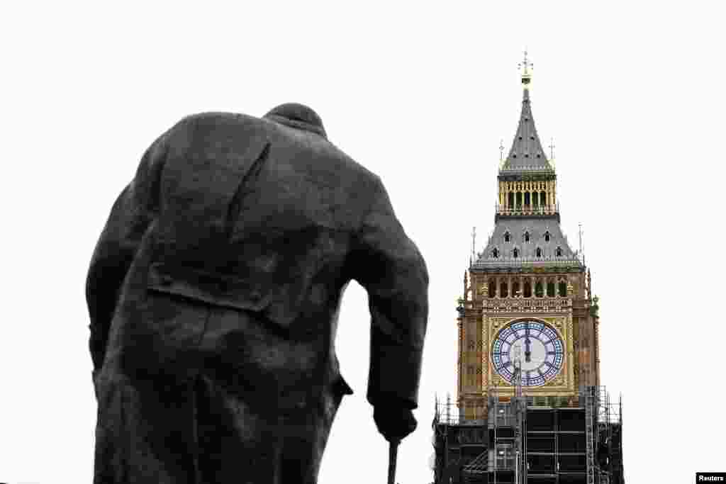 A clock face shows midday on Elizabeth Tower, more commonly known as Big Ben, with a statue of former British Prime Minister Winston Churchill in the foreground, ahead of New Year&#39;s Eve events when all four faces will be visible for the first time to ring