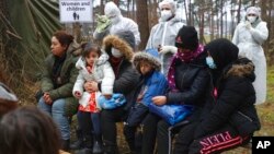 Migrants wait for an appointment with a Belarusian doctor at checkpoint "Kuznitsa" at the Belarus-Poland border near Grodno, Nov. 24, 2021. The EU has accused Belarus' government of orchestrating a migration surge in retaliation for EU sanctions. Belarus denies the assertion.