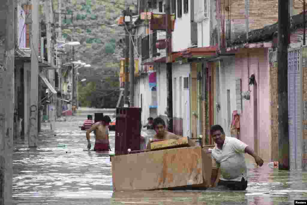 People move furniture through a flooded street in Tixtla, Mexico, Sept. 19, 2013. 