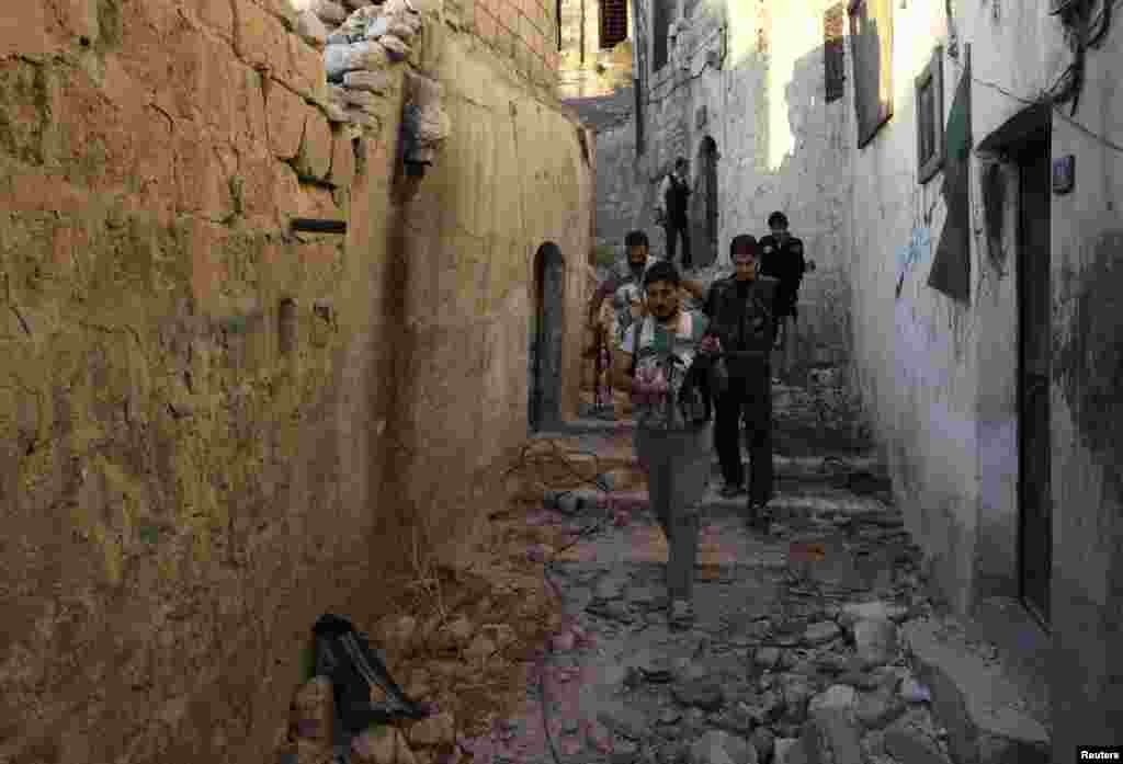 Free Syrian Army fighters walk with their weapons along a street around Hanano Barracks in Aleppo, Sept. 10, 2013.