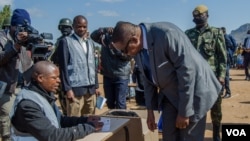 President Peter Mutharika gets instructions on how to vote from a presidisng officer, in Thyolo district. (Lameck Masina/VOA) 