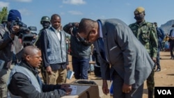 President Peter Mutharika gets instructions on how to vote from a presidisng officer, in Thyolo district. (Lameck Masina/VOA) 