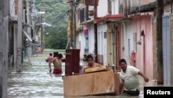 Warga memindahkan perabot rumah tangga melalui jalanan yang terendam banjir di Tixtla, Meksiko (19/8).