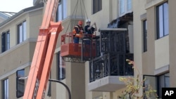 Workers with BELFOR Restoration Company look at a fourth floor balcony railing as it rests on the balcony below at the Library Gardens apartment complex in Berkeley, California, June 16, 2015.