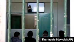 Prisoners sitting in a room while they watch a recorded music lesson in Avlona prison, north of Athens, Greece. (AP Photo/Thanassis Stavrakis)