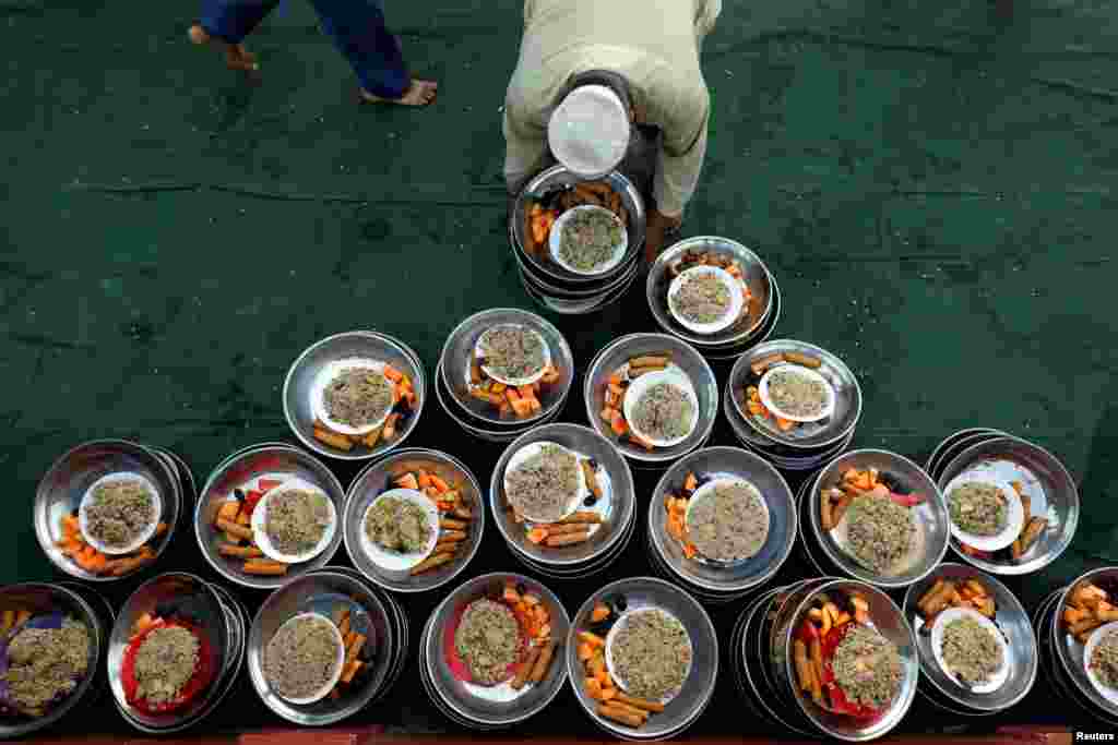 A volunteer put out plates of food for people to break fast during the fasting month of Ramadan, at a mosque in Karachi, Pakistan, May 7, 2019.