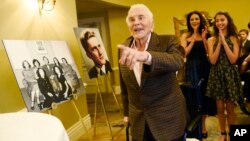 Actor Kirk Douglas arrives at his 100th birthday party as his daughter-in-law Catherine Zeta-Jones (second from right) and her daughter Carys applaud at the Beverly Hills Hotel, Dec. 9. 2016, in Beverly Hills, Calif.