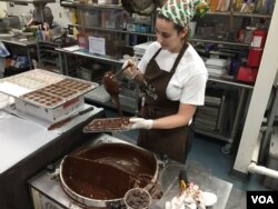 Chouquette employee Liz Smith pours warmed Guittard chocolate into molds to create the base for the company’s handcrafted caramels. (VOA Photo/J.Taboh)