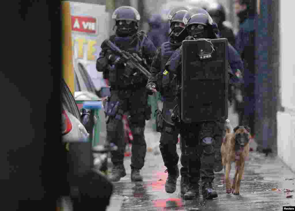 Armed French intervention police walk with a sniffer dog at the scene of a shooting in the street of Montrouge, near Paris, Jan. 8, 2015.