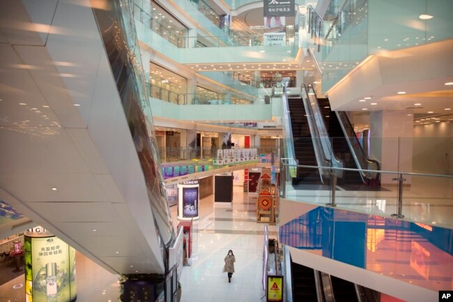 Una mujer con una mascarrilla protectora camina por un centro comercial casi vacío en Beijing, China, el 4 de febrero de 2020.