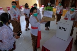 Petugas pemilu memakai masker pelindung saat pemilihan kepala daerah di Denpasar, Provinsi Bali, 9 Desember 2020. (Foto: Antara/Fikri Yusuf via REUTERS