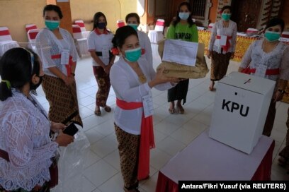 Petugas pemilu memakai masker pelindung saat pemilihan kepala daerah di Denpasar, Provinsi Bali, 9 Desember 2020. (Foto: Antara/Fikri Yusuf via REUTERS)