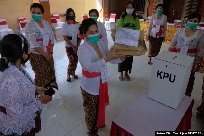Petugas pemilu memakai masker pelindung saat pemilihan kepala daerah di Denpasar, Provinsi Bali, 9 Desember 2020. (Foto: Antara/Fikri Yusuf via REUTERS)