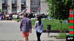 A young couple walks near a barricade outside the regional administration building in Ukraine's eastern city of Donetsk, occupied by pro-Russia insurgents, on May 14, 2014.