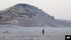 FILE - In this photo taken March 6, 2017, a Somali government soldier walks on the beach in Eyl, in Somalia's semiautonomous northeastern state of Puntland. Somali pirates have seized a small boat, kidnapped its Indian crew members, and are taking the ves