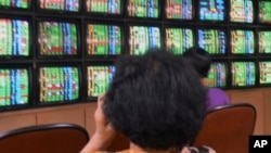 Taiwan stock investors watch trading information at a trading company.