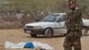 A member of the Kenyan security forces speaks on a telephone next to the body of one of those killed, outside the African Inland Church in Garissa, Kenya, July 1, 2012. 