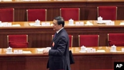 Bo Xilai walks past deserted seats after a plenary session of the National People's Congress in Beijing, China, March 9, 2012. 
