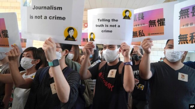 FILE - Supporters of Hong Kong journalist Bao Choy, fined for accessing a public database for an investigative report, hold placards outside a court in Hong Kong, April 22, 2021.