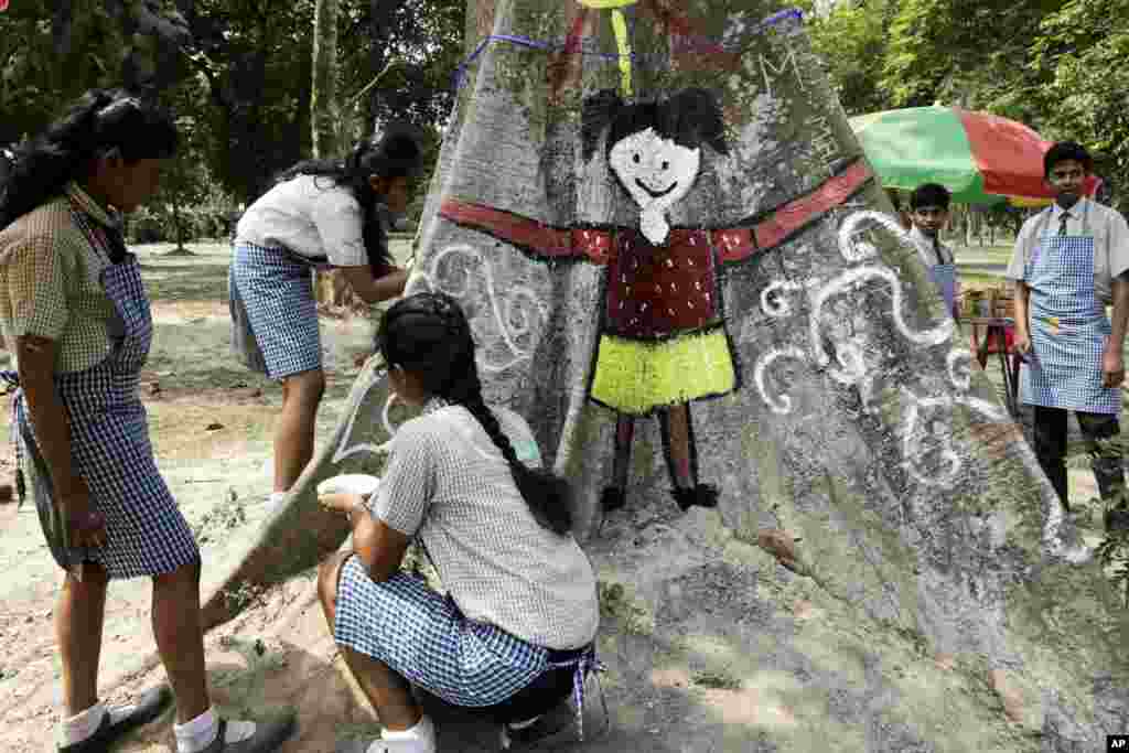 Siswa di India menggambari batang pohon di sebuah taman untuk memperingati Hari Bumi di Kolkata, 22 April 2017.
